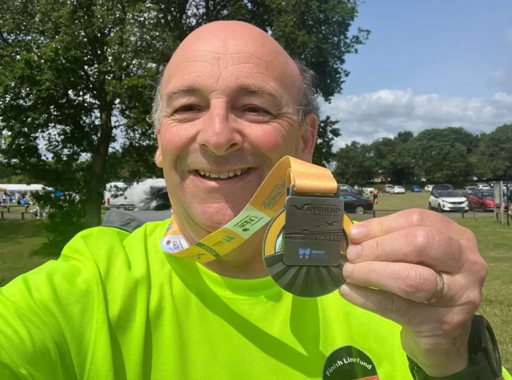 Maidstone Harrier club member of the month for April 2025, Andrew Burgess, holding his medal for Southend Half Marathon 2025
