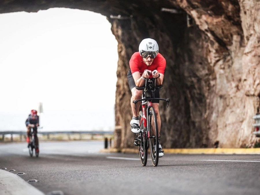 Anthony Warren in aero position on a time trial bike, riding through a rock tunnel during a triathlon