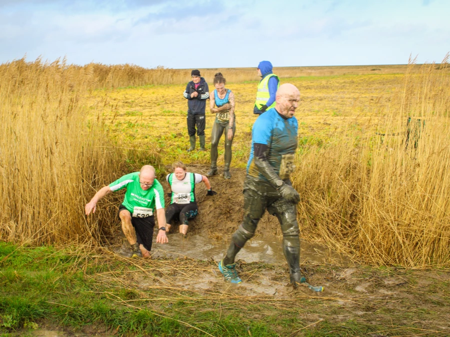 Runners climbing out of a muddy dyke at KFL Minnis Bay.