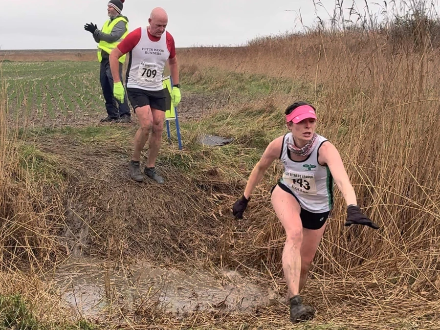 KFL Minnis Bay 2024 - Kent Fitness League runners in action crossing a muddy ditch. Maidstone Harriers
