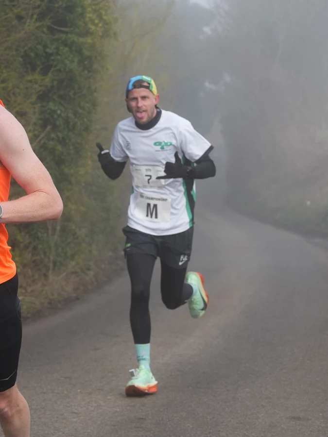 Phil Edmonds climbing a misty country lane during a road race.