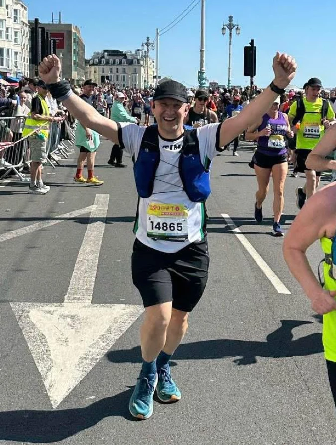 Tim Hilder of Maidstone Harriers celebrates finishing the Brighton Marathon with arms raised