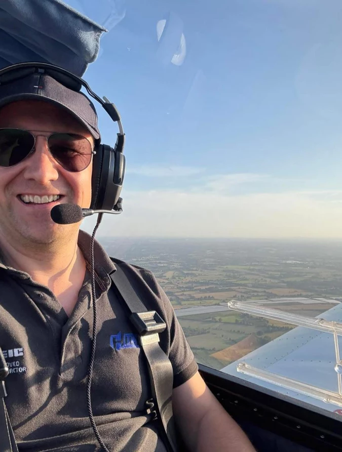 Maidstone Harriers member Tim Hilder smiling in the cockpit of his aeroplane while flying