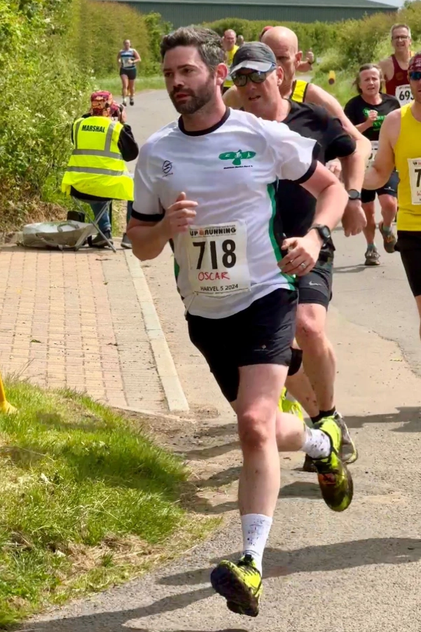 Oscar Phillips-Barrett racing Harvel 5 2024 in a Maidstone Harriers shirt, turning a corner past race marshals