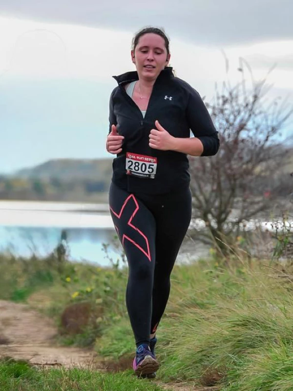 Debbie Addison running on a trail alongside a lake or river