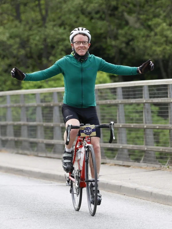 Mike Murdoch of Maidstone Harriers smiling while cycling across a bridge